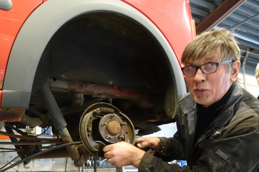 Mekanikar arbeider under ein bil på verkstaden